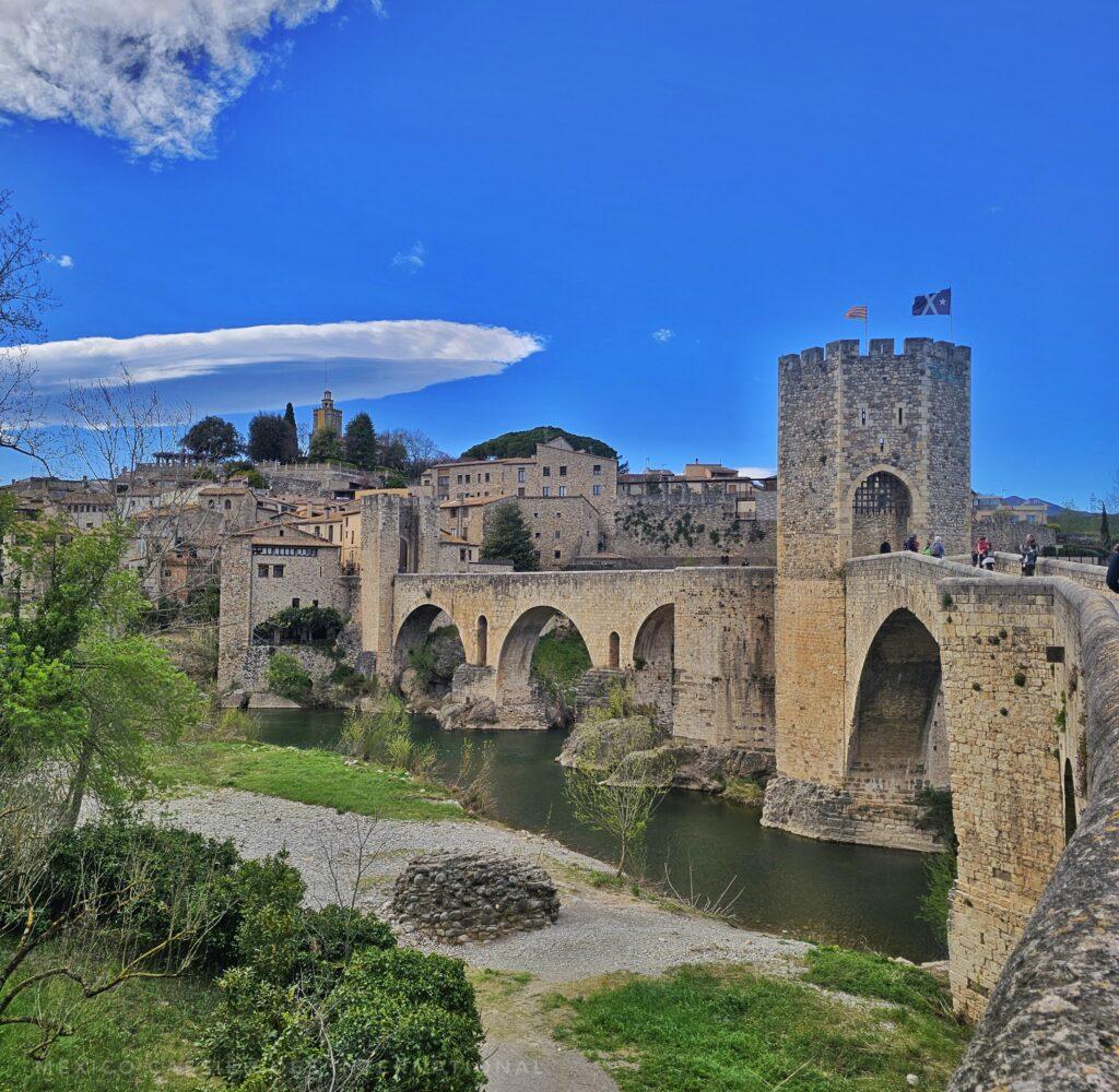blue sky, view of medieval bridge and tower over river into small medieval town