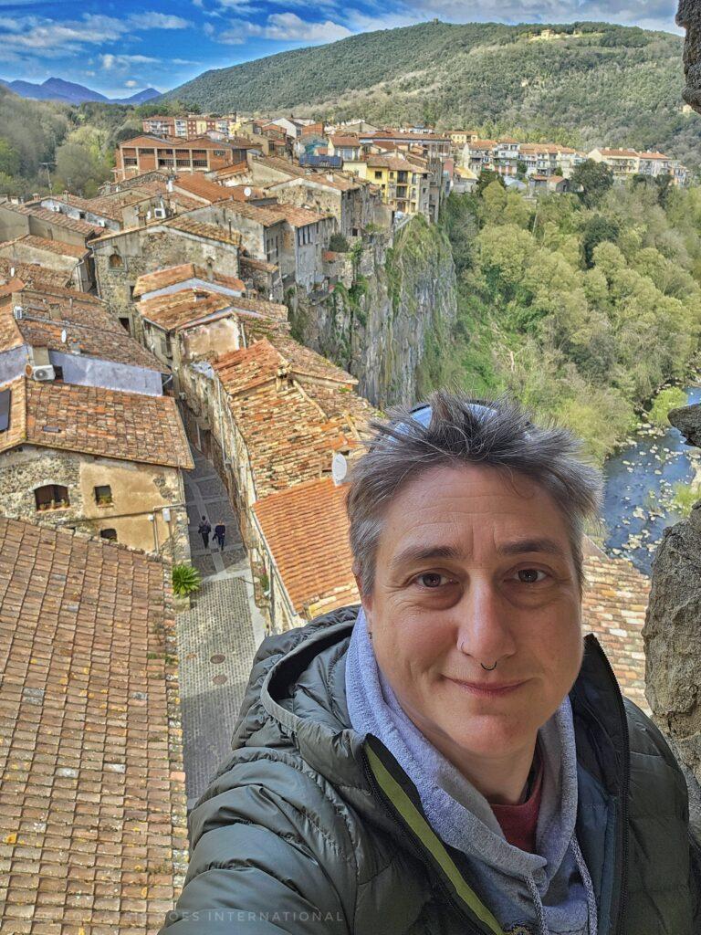 selfie of Cass in green jacket with medieval houses below