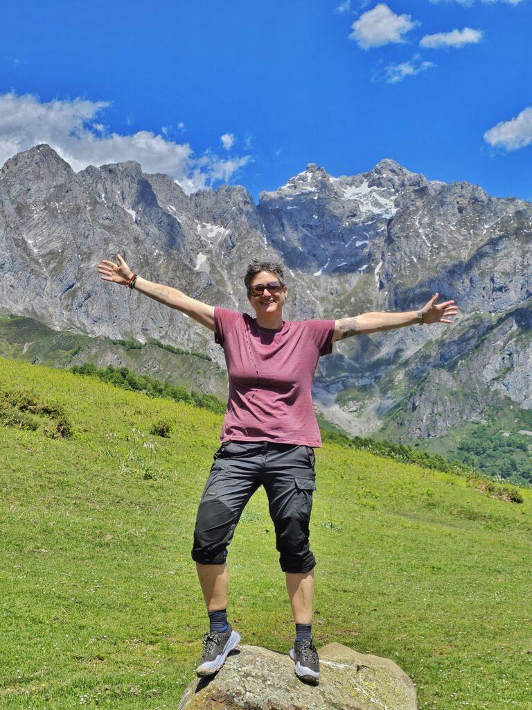 Cass in red tshirt standing on rock with mountains behind