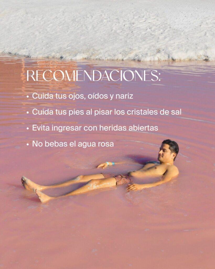 man lying partially submerged in pink water, white text (in Spanish) explaining how to keep safe (tread carefully on the salt, keep eyes and mouth away)