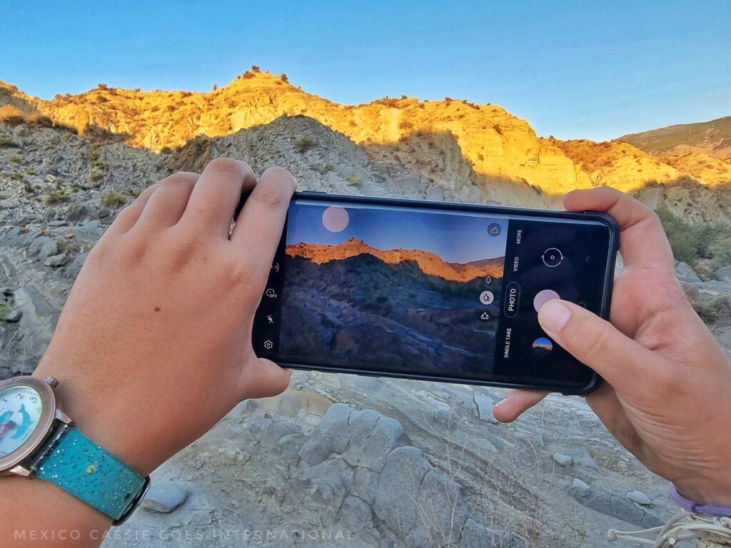 photo of someone's phone as they take a photo of some mountains