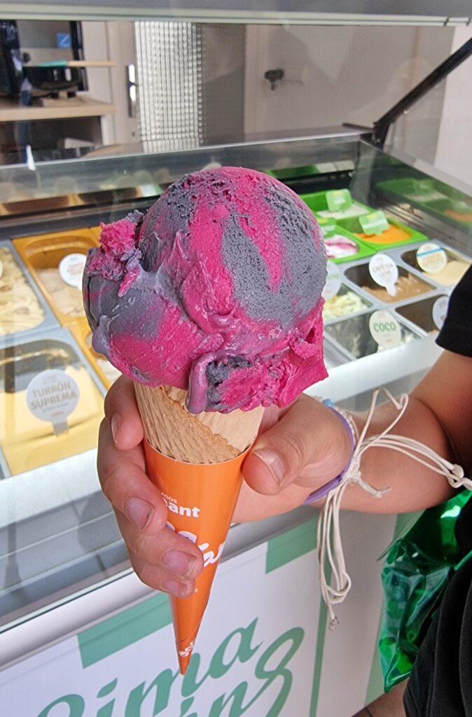 kid's hand holding purple and pink ice cream