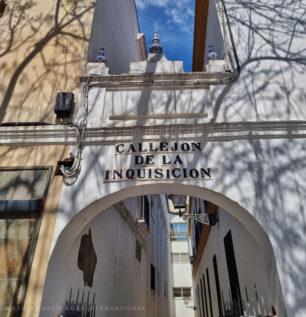 white archway at start of narrow alley way - sign reading Callejon de la Inquision