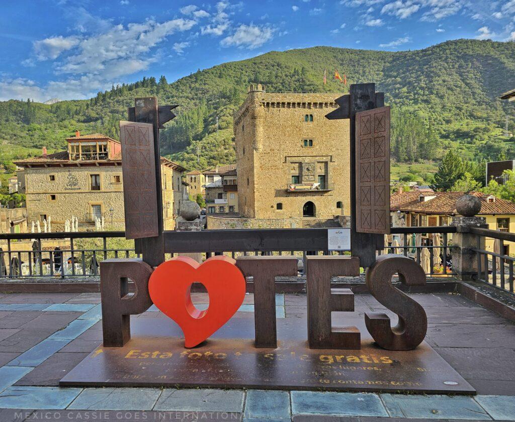 metal Potes sign where the o is a red heart, above is an iron frame with the tower and hills behind