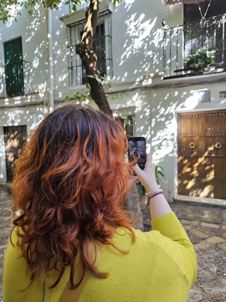 woman in yellow with red hair taking a photo (photo taken from the back)