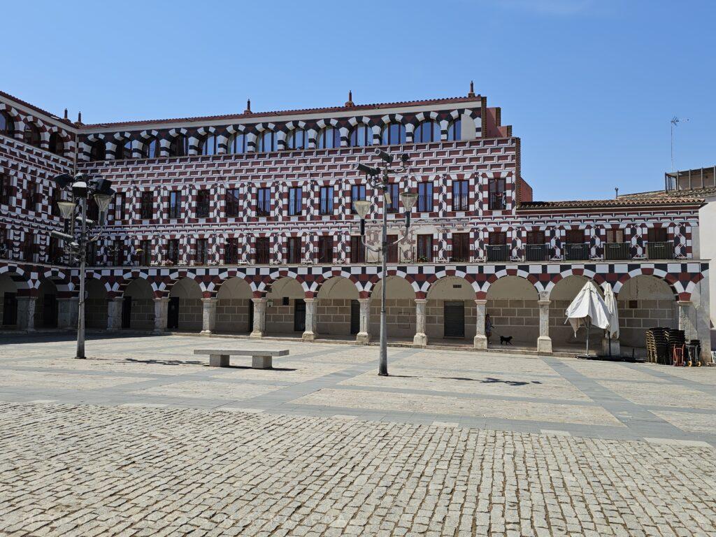 Plaza Alta - freshly painted red and white geometric patterns on buildings - arches on ground floor, part of it missing