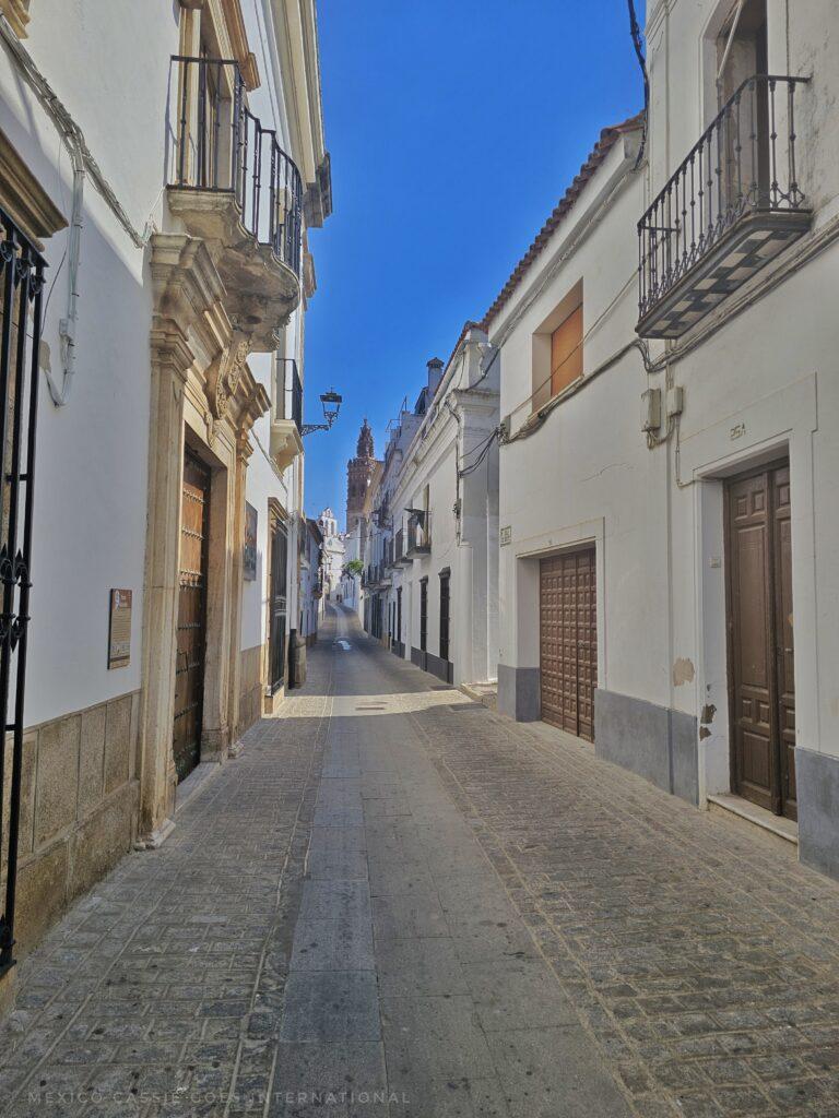 narrow street with white houses on either side of road, blue sky