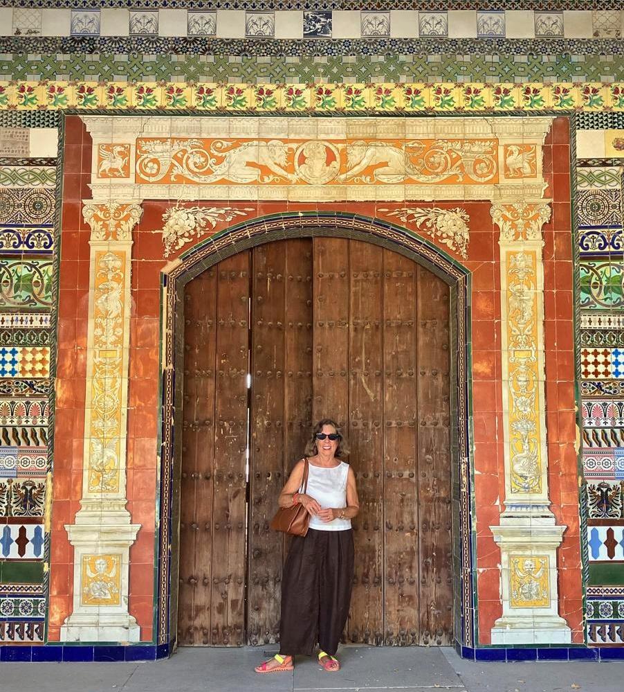 woman in sunglasses standing in front of a wooden door surrounded by beautiful tiles