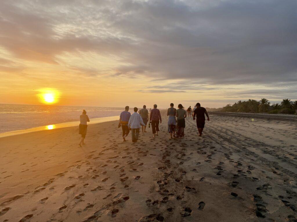 group walking on beach at sunset