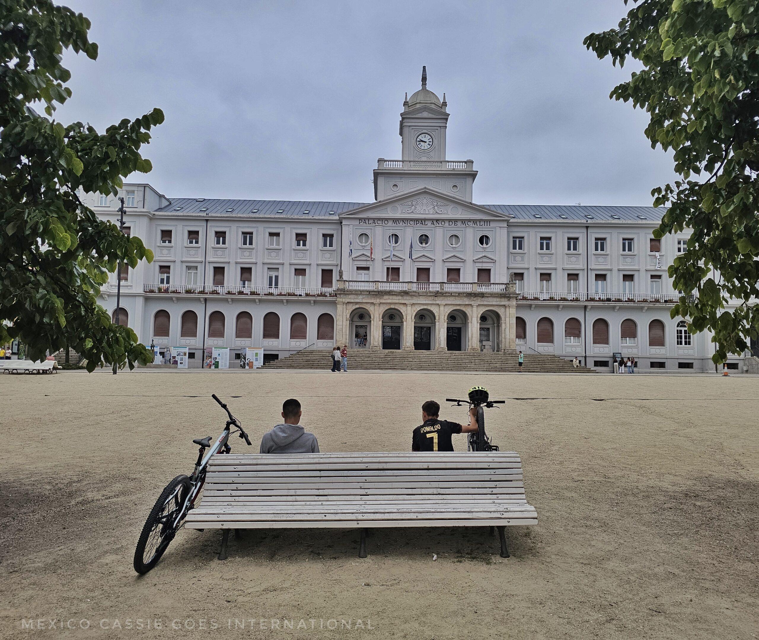 Ferrol's imposing town hall, empty plaza and kids with two bikes sitting on bench
