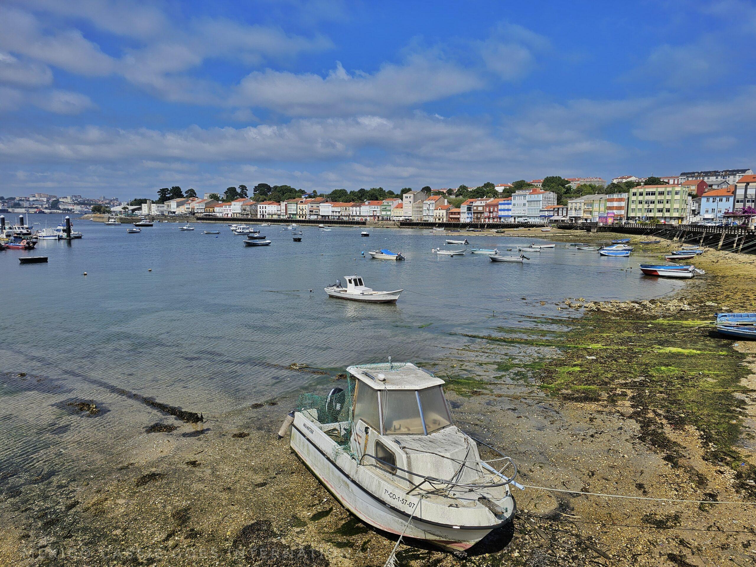 small boat in shallow water, town behind
