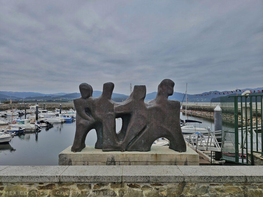 sculpture in the port of Ortigueria, 4 concrete people, very stylised and chunky