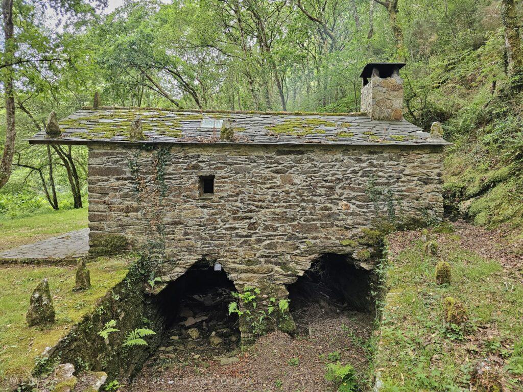 stone mill with two gaps for stream to run through building, forest all around