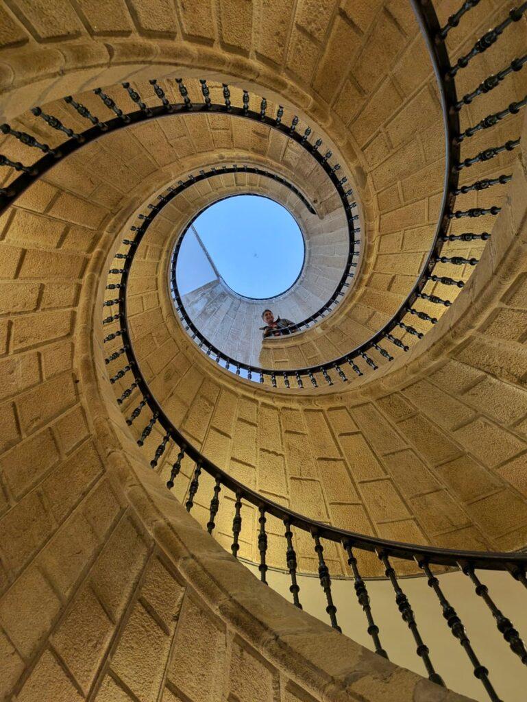 Cass looking down at someone taking photo UP the incredible spiral staircase
