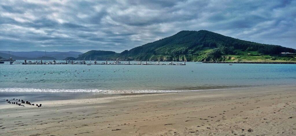 Beach at Cariño - moody sky, sand, green hill in distance