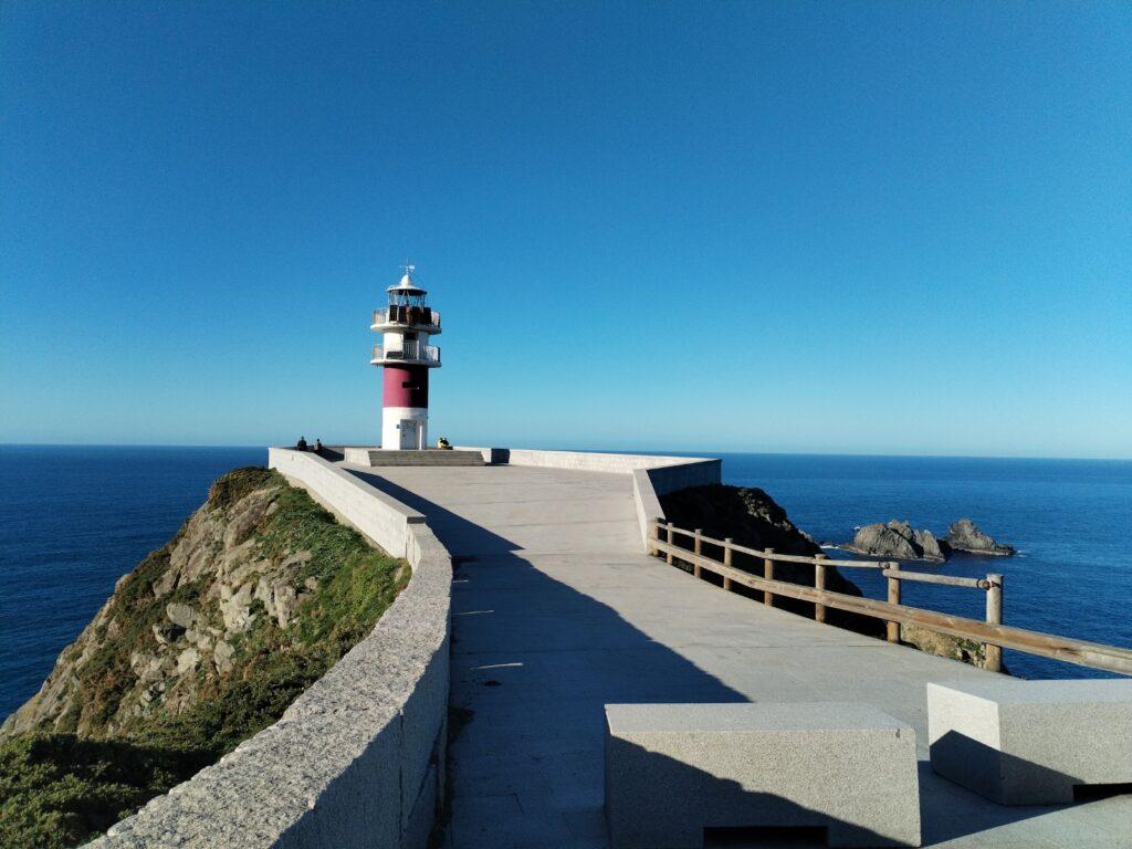 lighthouse at Cabo Ortegal - path leading up to it, cliffs on left, blue sky and blue sea