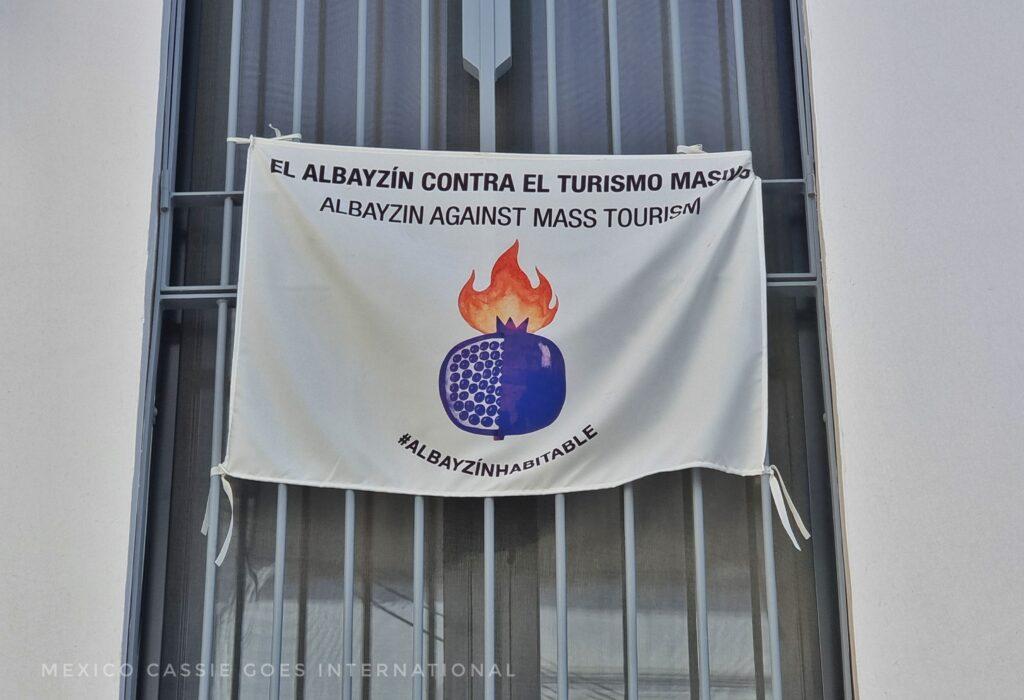 white flag from Granda with a picture of a pomegranate burning. Says Albayzín against mass tourism