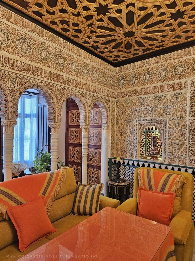 living room with table and sofas, walls in alhambra style, arches behind the sofas