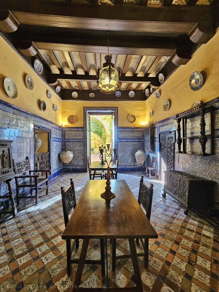 photo of dining room, table in middle, open door at end, blue tiles on walls, yellow painted above tiles