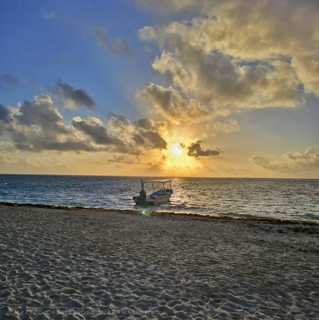 sunrise on the beach, sand, water, small boat, clouds and sun just rising