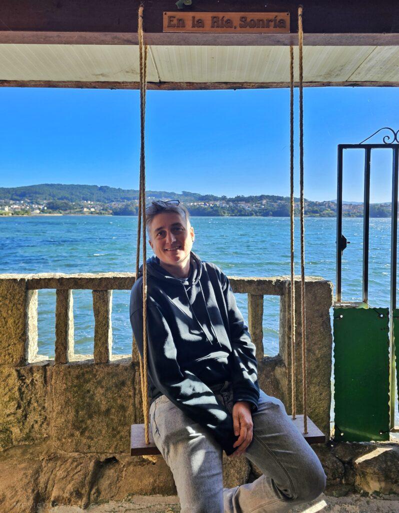 cass smiling while sitting on a swing in front of the water