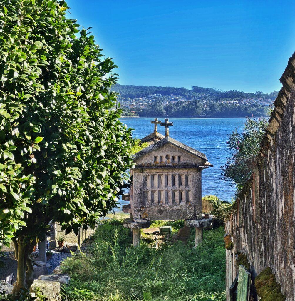 a typical granary made of concrete on legs. sea behind, wall on right, tree on left