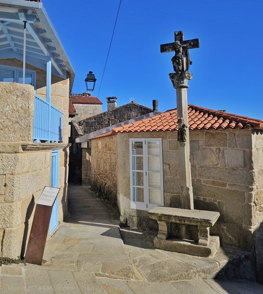 house with stone bench and cruicero outside it