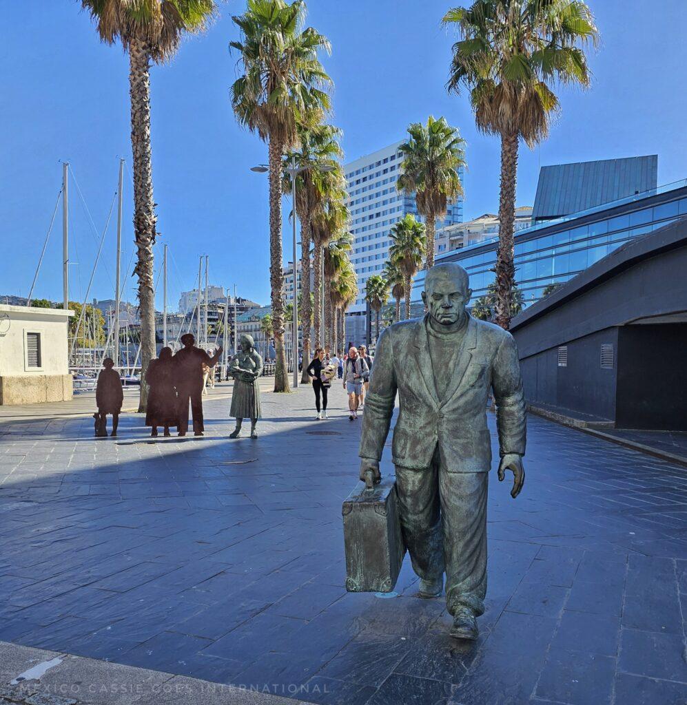 moving sculpture of a family watching a man walk towards the port. woman holding baby and man are detailed, rest of family is plain