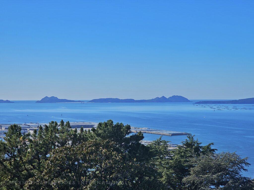 view over trees to the islas cíes, blue sea, blue sky