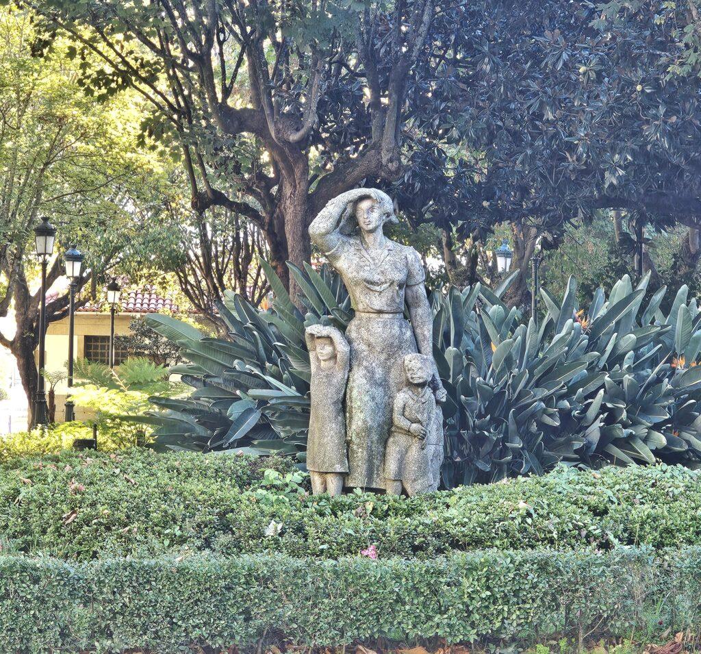 sculpture of a woman and two kids amongst greenery