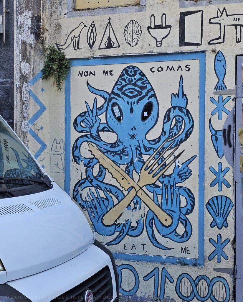 blue pulpo holding up a finger, knife and fork in front, text says non me comas (don't eat me)