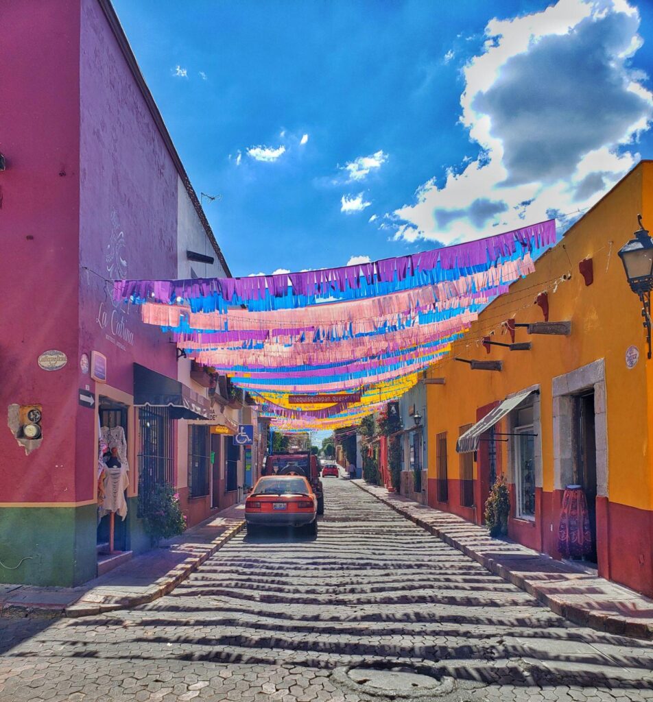 colourful buildings, cars on road between buildings, decoration over road